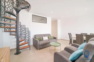 a living room with couches and a spiral staircase at Palmeiras by MTPhomes in Albufeira