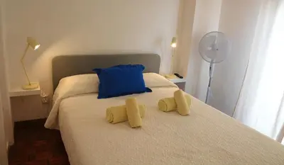 a bed with a blue pillow and two yellow slippers at Blife Chelsya private apartment in Faro