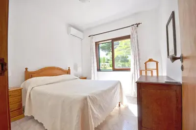 a white bedroom with a bed and a window at Casa da Palmeira in Quarteira