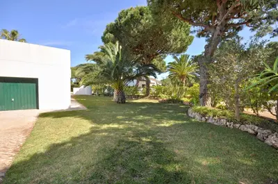 a yard with palm trees and a building at Casa da Palmeira in Quarteira