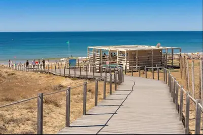 a boardwalk leading to a beach with a building at Luxury Apartment Salgados Village in Guia