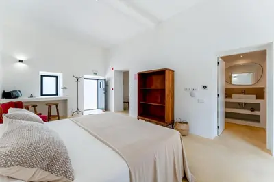 a white bedroom with a bed and a bathroom at Uma Casa Rural in Santa Bárbara de Nexe