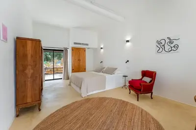 a bedroom with a bed and a red chair at Uma Casa Rural in Santa Bárbara de Nexe