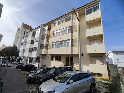 a apartment building with cars parked in front of it at Algarve, cozy T1plus1 apartment in the centre of Quarteira in Quarteira