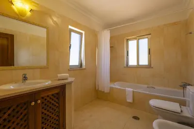 a bathroom with a sink and a tub and a toilet at Villa Joana by Villa Select in Albufeira