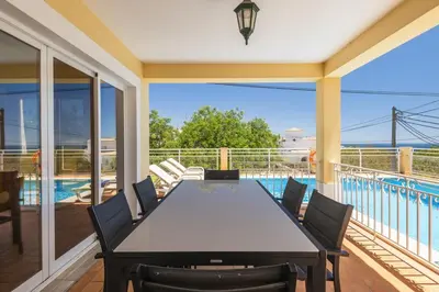 a dining room with a table and chairs on a balcony at Villa Luana by Villa Select in Albufeira