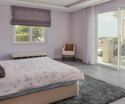 a bedroom with a bed and a window and a chair at Stunning home with nice pool close to the beach in Loulé