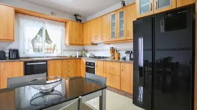 a kitchen with wooden cabinets and a black refrigerator at Casa Donis 2021 in Albufeira