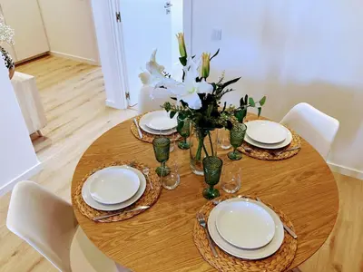 a wooden table with plates and a vase of flowers at Apartamento T2 Moderno no Centro de Faro - ML - Market Tower in Faro