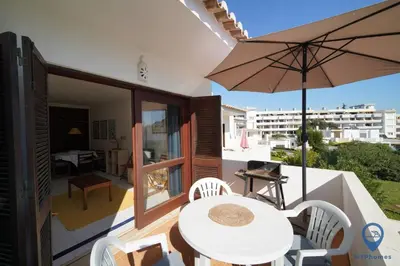 a white table and chairs with an umbrella on a balcony at Balaia Mar 63D By MTPhomes in Albufeira