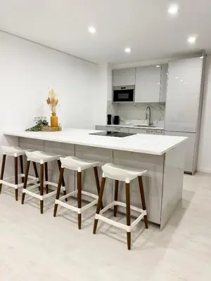 a kitchen with a large white island with bar stools at Sunrise Apartment in Albufeira