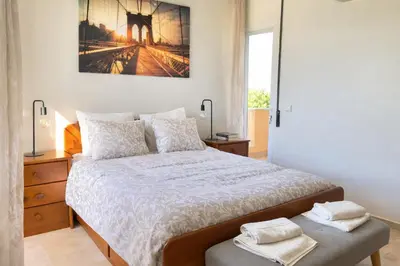 a white bedroom with a large bed and a window at Apartamento Terraços do Vale in Albufeira