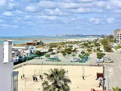 a view of a beach with cars parked on the sand at Beach Holiday House T1 in Quarteira