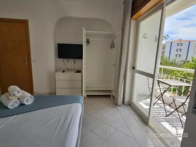 a bedroom with a bed and a balcony with a television at Blife Allya private apartment in FAO