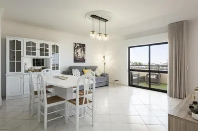 a kitchen and living room with a white table and chairs at Dunas - Sea view near the beach by HD in Quarteira