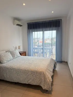 a bedroom with a bed and a large window at Majesti Algarve Apartment in Albufeira