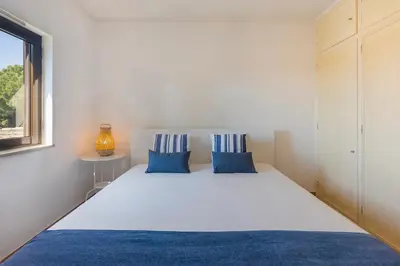 a bedroom with a large white bed with blue pillows at Cozy Villa next to the Golf Course by Algarve Dream Holidays in Quarteira