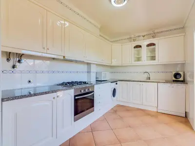 a kitchen with white cabinets and a stove top oven at Apartamento Mélias, 2 quartos e piscina, Vilamoura in Vilamoura