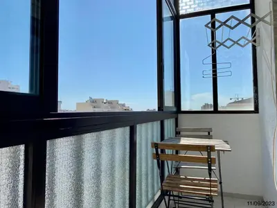 a balcony with two chairs and a table and windows at Blife Anya private apartment in Faro