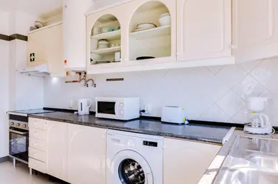 a kitchen with white cabinets and a washing machine at Blife Anya private apartment in Faro