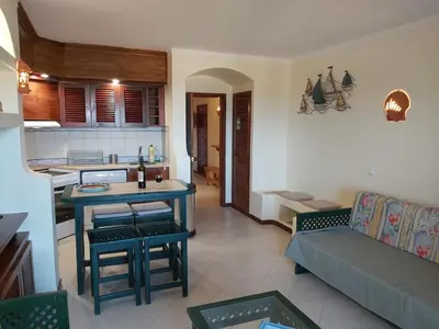 a kitchen and a living room with a table and a couch at Albufeira Apartment, Pool and Sea view in Albufeira