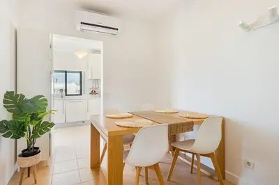 a dining room with a wooden table and white chairs at Salgados Retreat -Steps from the Beach at Homesbyfc in Guia