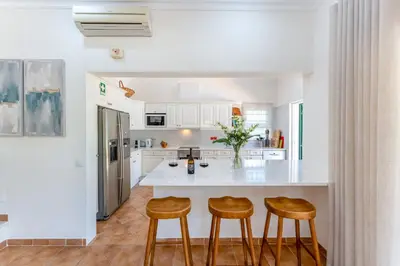 a kitchen with a white counter and stools at Villa Mia - Vale do Lobo in Vale do Lobo