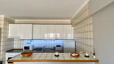 a living room with a black leather couch and a table at Sea House Apartment - Private Condo with 4 Pools, Jacuzzi & Tennis Court in Albufeira