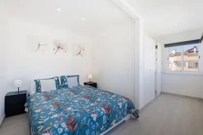 a white bedroom with a bed and a table at Let the sun come in - walking to the beach by Algarve Dream Holidays in Albufeira