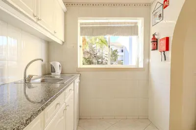 a white kitchen with a sink and a window at #344 Edificio Marina Sol by Home Holidays in Branqueira