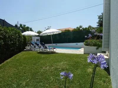 a yard with chairs and umbrellas and a pool at Villa Jose in Olhos de Água