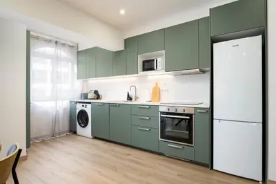 a kitchen with green cabinets and a washer and dryer at LIA - Quarteira in Quarteira