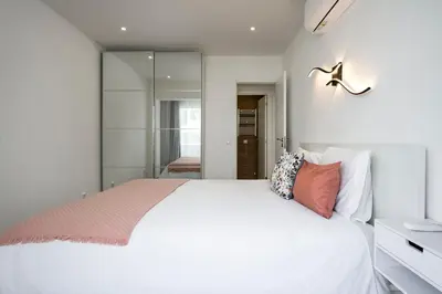 a bedroom with a white bed and a mirror at LIA - Quarteira in Quarteira