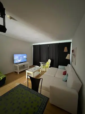 a living room with a white couch and a tv at Marina de Albufeira - Apartamentos Turísticos da Orada in Albufeira
