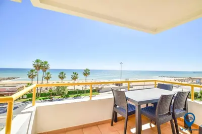 a balcony with a table and chairs and the beach at Praia Mar by MTPhomes in Quarteira