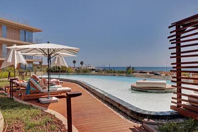 a person laying in chairs by a swimming pool with an umbrella at New Beach Apartment in Quarteira