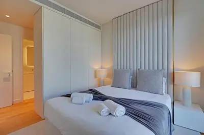 a bedroom with a white bed with towels on it at New Beach Apartment in Quarteira