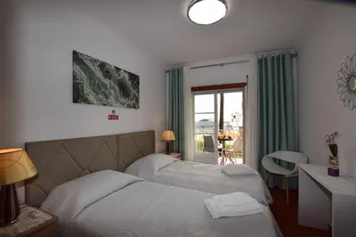 a bedroom with two beds and a table and a window at Apartamento Albufeira in Albufeira