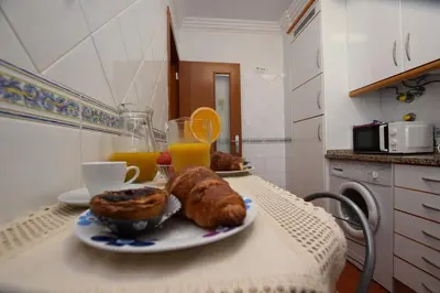 a table with a plate of pastries and orange juice at Apartamento Albufeira in Albufeira