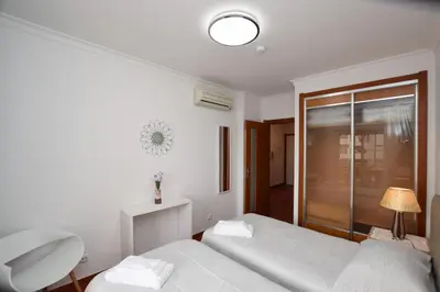 a white bedroom with a bed and a glass door at Apartamento Albufeira in Albufeira