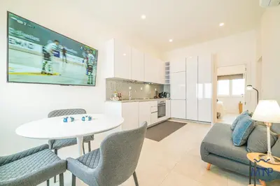 a white kitchen with white cabinets and a lamp at Maria Sardinha by MTPhomes in Ferreiras