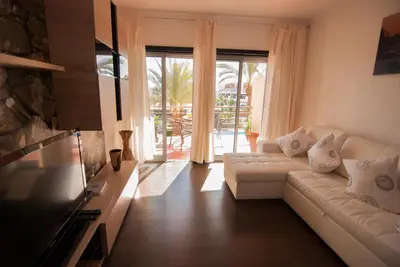 a living room with a white couch and a large window at Apartamento Albufeira- Descobrimentos in Albufeira