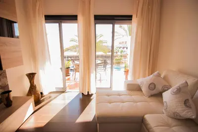 a living room with a white couch and a large window at Apartamento Albufeira- Descobrimentos in Albufeira