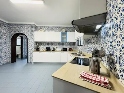 a kitchen with white cabinets and blue and white tiles at Vilamoura Summer Villa 2 With Pool by Homing in Vilamoura