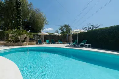 a large blue swimming pool with chairs and umbrellas at Villa Juliet in Boliqueime