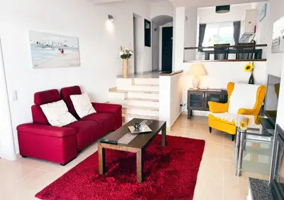 a living room with a red couch and a fireplace at Windmill Hill Apartment in Albufeira