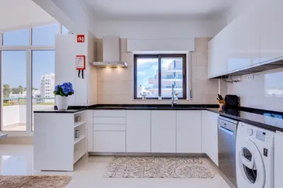 a white kitchen with a sink and a dishwasher at Carteia Beachfront at Praia da Gaivota in Quarteira