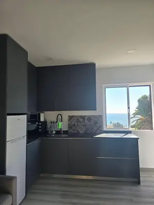 a kitchen with black cabinets and a large window at O Forte by MTPhomes in Albufeira