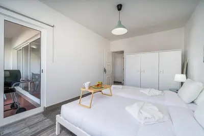 a white bedroom with a white bed and a table at Panoramic Sea Views & Balcony BBQ by HostWise in Albufeira