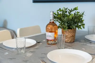 a bottle of wine sitting on a table with plates and glasses at Top Strip Albufeira in Albufeira